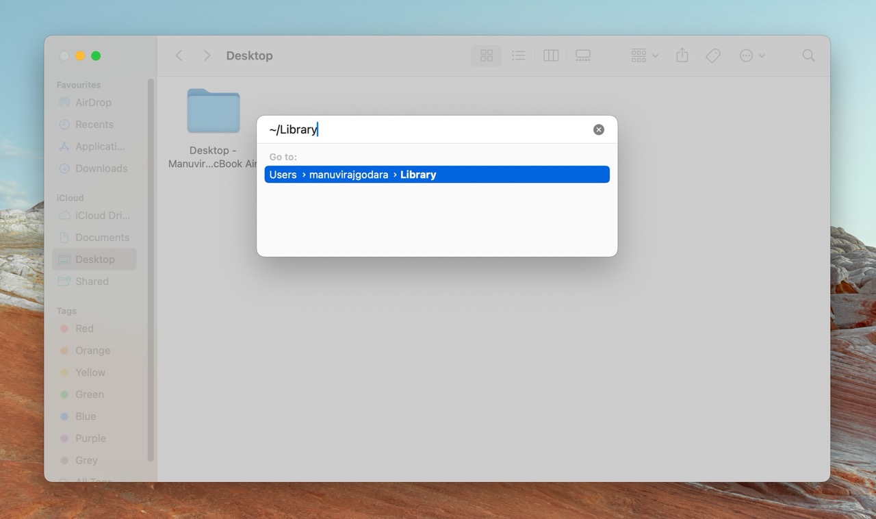 A Finder window on a Mac displaying a Go To Folder dialog box with the path "~/Library" entered, leading to the user's Library folder.